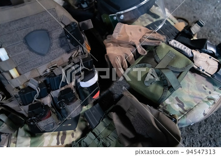 Army body armor, helmet and ammunition, Kalashnikov assault rifle with matrons and first aid tourniquet composition on brown wood. Army body armor. flat laying. military concept. Army body armor, helmet and ammunition, Kalashnikov assault rifle with matrons and first aid tourniquet composition on brown wood. Army body armor. flat laying. military concept. 94547313