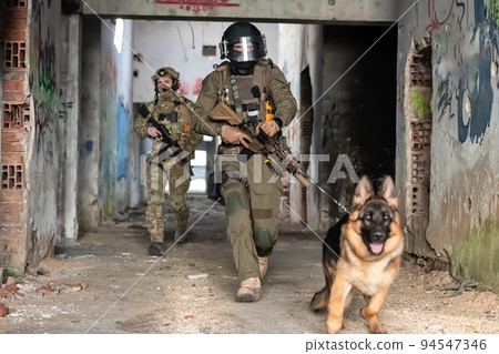 Modern Warfare Soldiers with military working dog in action on the battlefield.  94547346