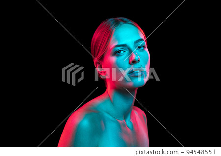 Closeup portrait of young pretty woman with naked shoulders in red neon light on dark background. Art, creativity, fashion, style Closeup portrait of young pretty woman with naked shoulders in red neon light on dark background. Art, creativity, fashion, style 94548551