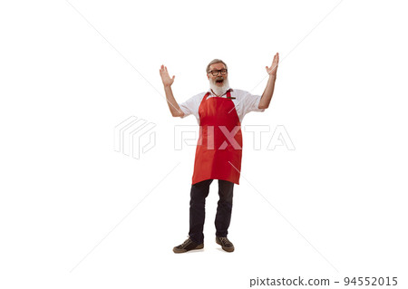 Portrait of senior man, cheerful salesman in red apron posing isolated over white background. Welcoming customers 94552015
