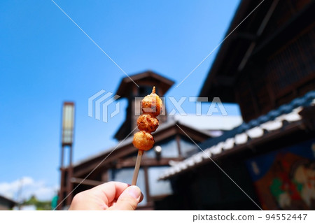 Woman's hand holding mitarashi dango while eating while walking around the old town 94552447