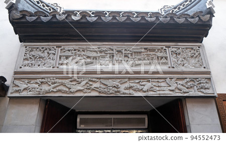 Richly carved stone bass-relief plaque on the doorway of the house in the Grand Canal, ancient town of Yuehe in Jiaxing, Zhejiang Province, China 94552473