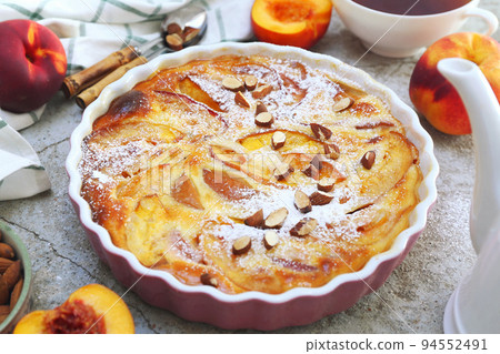 Nectarine clafoutis (flan) with almonds, icing sugar dressing and cup of tea 94552491