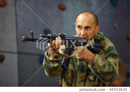 The soldier in the performance of tasks in camouflage and protective gloves, holding a gun. The zone of military operations. The soldier in the performance of tasks in camouflage and protective gloves, holding a gun. The zone of military operations. 94553630