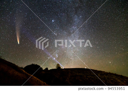 Small silhouette of a scientist with flashlight on his head pointing bright beam of light on starry sky with C/2020 F3 (NEOWISE) comet with light tail. Space exploration concept. 94553951