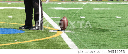 Football on the tee for kickoff with thr referee standing next to the ball 94554053