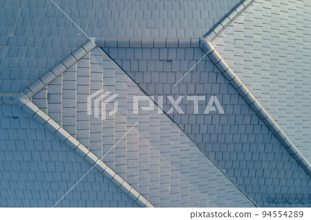 Closeup of house roof top covered with ceramic shingles. Tiled covering of building Closeup of house roof top covered with ceramic shingles. Tiled covering of building 94554289