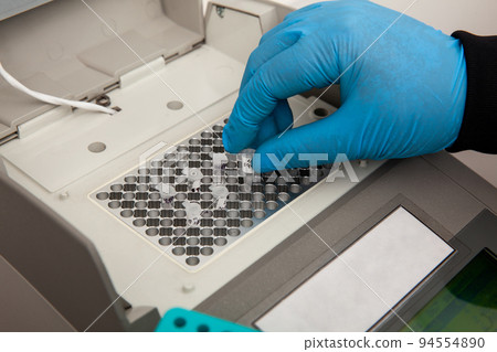 Closeup of a scientist hand while working at the laboratory with a thermal cycler. Polymerase chain reaction technique. PCR technique 94554890