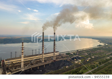 Aerial view of high chimney pipes with grey smoke from coal power plant. Production of electricity with fossil fuel. Aerial view of high chimney pipes with grey smoke from coal power plant. Production of electricity with fossil fuel. 94555159