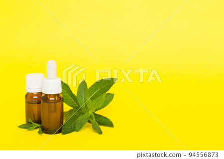 Natural Mint Essential Oil in a Glass Bottle. organic cosmetics with herbal extracts of mint on colored background Natural Mint Essential Oil in a Glass Bottle. organic cosmetics with herbal extracts of mint on colored background 94556873