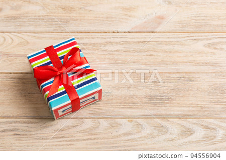 Wrapped christmas or other holiday handmade present in paper with colored ribbon. Present box, decoration of gift on table, top view with copy space Wrapped christmas or other holiday handmade present in paper with colored ribbon. Present box, decoration of gift on table, top view with copy space 94556904