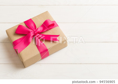 Wrapped christmas or other holiday handmade present in craft paper with colored ribbon. Present box, decoration of gift on table, top view with copy space Wrapped christmas or other holiday handmade present in craft paper with colored ribbon. Present box, decoration of gift on table, top view with copy space 94556905