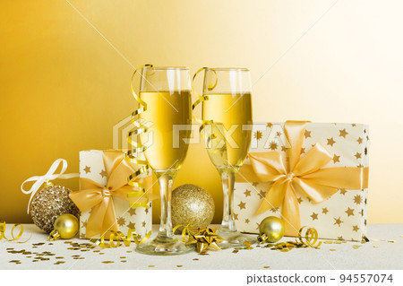 Champagne glasses and christmas decor on colored holiday background. Flat lay New Year decorations Champagne glasses and christmas decor on colored holiday background. Flat lay New Year decorations 94557074