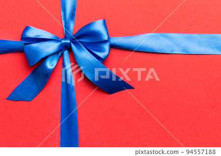 Top view of blue ribbon rolled and blue bow isolated on colored background. Flat lay with copy space 94557188