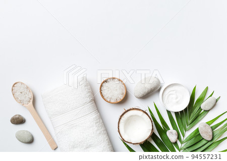 Coconut with jars of coconut oil and cosmetic cream on colored background. Top view. Free space for your text. Natural spa coconut cosmetics and organic treatment concept Coconut Spa composition 94557231