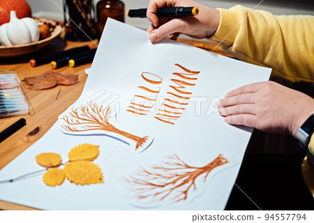Autumn Season Drawing, How to draw fall lettering drawing and painting. Female hands drawing autumn lettering on the table with paints, brushes and autumn leaves Autumn Season Drawing, How to draw fall lettering drawing and painting. Female hands drawing autumn lettering on the table with paints, brushes and autumn leaves 94557794