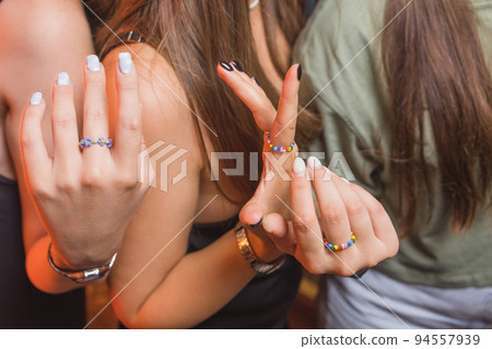 close-up view of a man's hand showing a ring with an LGBT rainbow wristband. 94557939