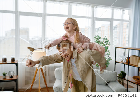 Loving father piggyback riding happy laughing daughter 94559141