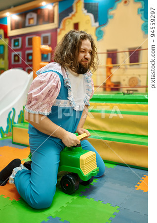 Funny adult man and woman like babies driving toy car Funny adult man and woman like babies driving toy car 94559297