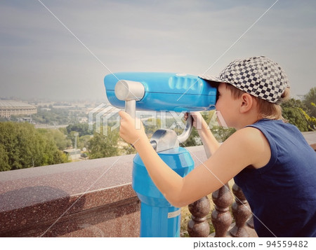 boy observing city panorama through stationary binoculars boy observing city panorama through stationary binoculars 94559482