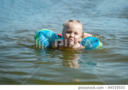 cute little girl swimming in sea on rubber ring.  94559503