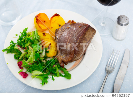 Roasted boneless beef with baked potatoes and greens 94562397