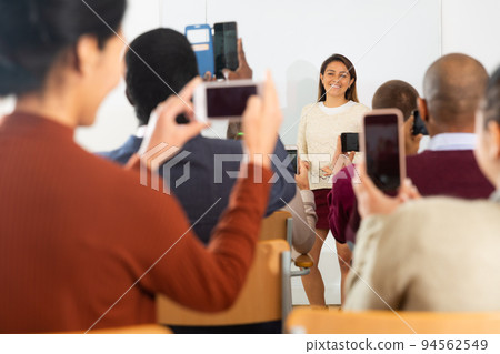 Latina woman in front of chalkboard and people shooting on smartphones her 94562549