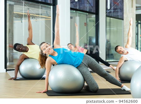 Young woman exercising with pilates ball during group class Young woman exercising with pilates ball during group class 94562600