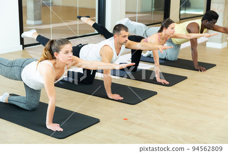 Sporty people doing pilates exercises in fitness studio Sporty people doing pilates exercises in fitness studio 94562809