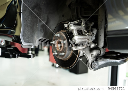 Disc car close up - mechanic unscrewing automobile parts while working under a lifted auto Disc car close up - mechanic unscrewing automobile parts while working under a lifted auto 94563721