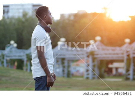 African American man stands exploring big park in back lit African American man stands exploring big park in back lit 94566481