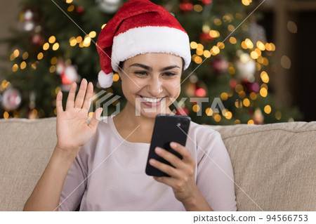 Happy Indian girl in Christmas hat talking on video call Happy Indian girl in Christmas hat talking on video call 94566753