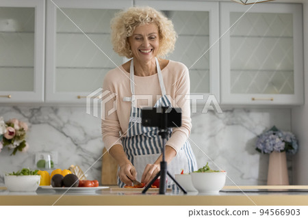Cheerful mature retired blogger woman recording cooking video Cheerful mature retired blogger woman recording cooking video 94566903