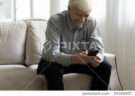 Happy cheerful senior man typing on smartphone, using online app Happy cheerful senior man typing on smartphone, using online app 94566907
