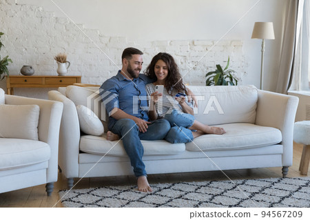 Couple enjoy e-shopping at home using smartphone and credit card Couple enjoy e-shopping at home using smartphone and credit card 94567209