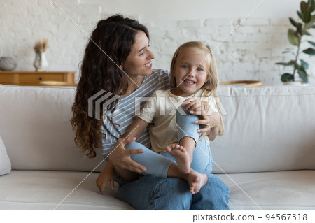 Daughter sits on Hispanic mothers laps smile looking at camera Daughter sits on Hispanic mothers laps smile looking at camera 94567318