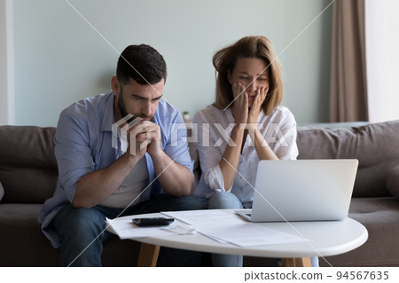 Frustrated worried millennial husband and wife reading bankrupt message Frustrated worried millennial husband and wife reading bankrupt message 94567635