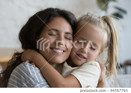 Closeup happy Latina young mother strong cuddle little blonde daughter 94567765
