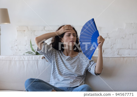 Overheated Hispanic woman wave fan, cooling herself at hot day Overheated Hispanic woman wave fan, cooling herself at hot day 94567771