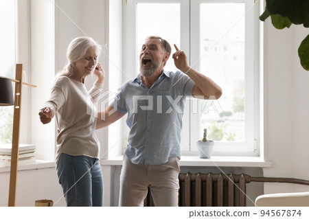 Joyful excited mature retired couple having fun at home party 94567874