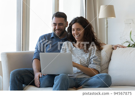 Laughing couple watch family comedy movie use laptop 94567875