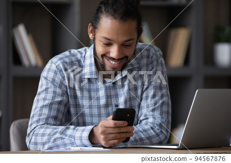 Happy handsome young African American man using mobile apps. 94567876