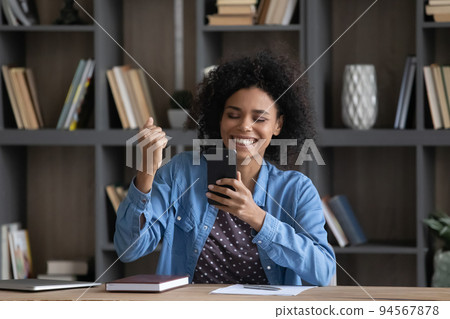 Happy young African American woman celebrating internet success. Happy young African American woman celebrating internet success. 94567878