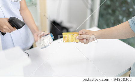 Credit card payment, Male patient pays by credit card to a pharmacist in a pharmacy, Get service at a community pharmacy , Pharmacist or cashier scanning medicinal products at checkout. Credit card payment, Male patient pays by credit card to a pharmacist in a pharmacy, Get service at a community pharmacy , Pharmacist or cashier scanning medicinal products at checkout. 94568303