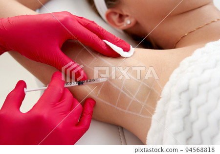 Doctor makes injections of botulinum toxin in the underarm area against hyperhidrosis in beauty salon. Female cosmetology and problems with sweating concept 94568818