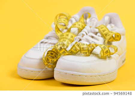 Centimeter in yellow color curled on white trainers 94569148