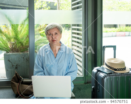 relax, vacation, travel, portrait of senior adult elderly asian woman 60s smiling using the computer laptop while waiting for her travel time. 94570751
