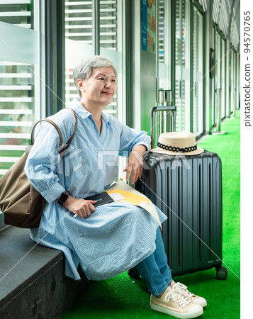 relax, vacation, travel, portrait of senior adult elderly asian woman 60s smiling sitting with suitcase luggage bag while waiting for her travel time. relax, vacation, travel, portrait of senior adult elderly asian woman 60s smiling sitting with suitcase luggage bag while waiting for her travel time. 94570765