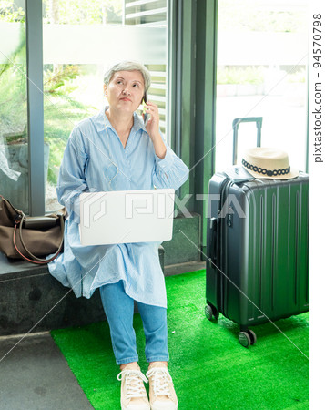 relax, vacation, travel, portrait of senior adult elderly asian woman 60s smiling using the computer laptop and smartphone while waiting for their travel time. relax, vacation, travel, portrait of senior adult elderly asian woman 60s smiling using the computer laptop and smartphone while waiting for their travel time. 94570798