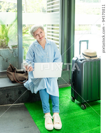 relax, vacation, travel, portrait of senior adult elderly asian woman 60s smiling using the computer laptop and smartphone while waiting for their travel time. relax, vacation, travel, portrait of senior adult elderly asian woman 60s smiling using the computer laptop and smartphone while waiting for their travel time. 94570811